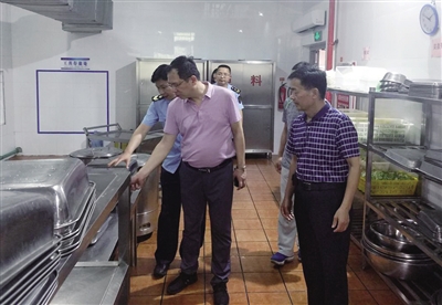 荔城区市场监管局局长黄志雄(左一)察看中高考期间校园食堂后厨卫生